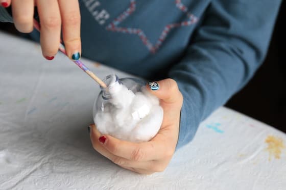 Filling clear plastic ornament with cotton balls