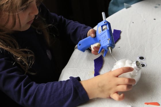 Child gluing purple scarf to snowman