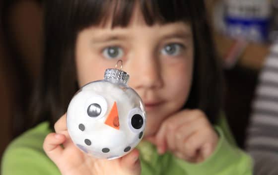 Child holding finished snowman ornament