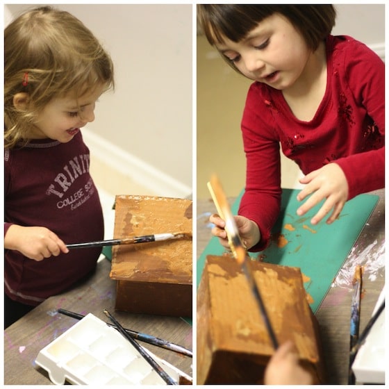 toddlers painting cardboard house brown