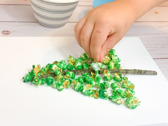 child gluing popcorn to stick