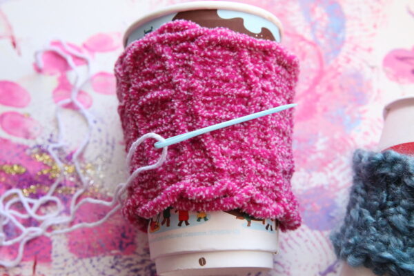 pink coffee cup sleeve with sewing needle