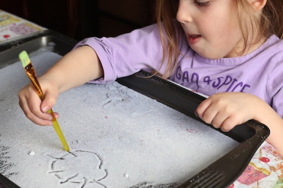 preschooler drawing a sun in a tray of salt