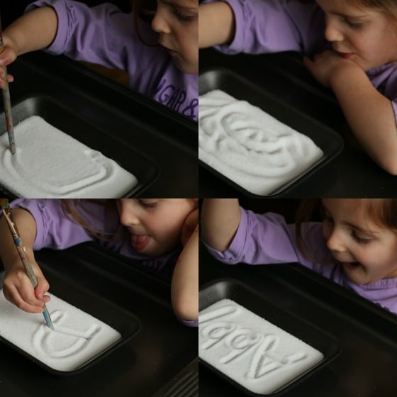 Preschooler drawing shapes and writing her name in salt