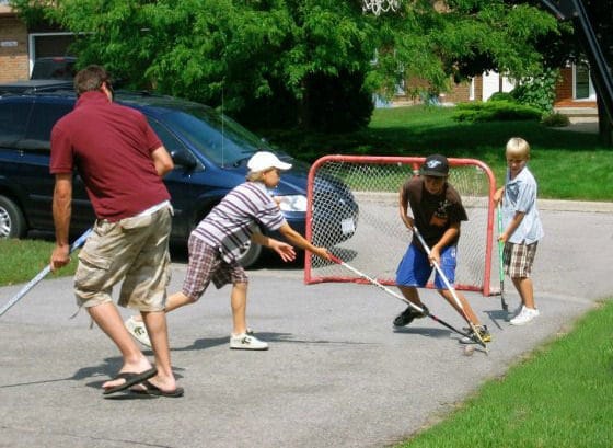 dad and kids playing road hockey