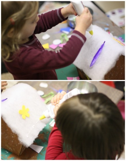 toddlers gluing quilt batting to roof of cardboard house