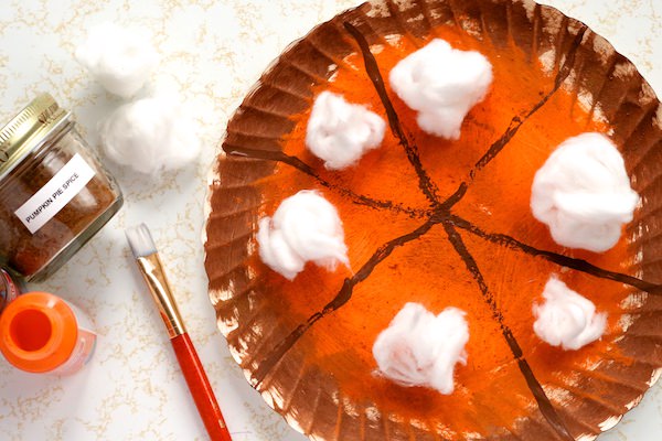 Scented pumpkin pie paper plate craft beside paint and jar of pumpkin pie spice