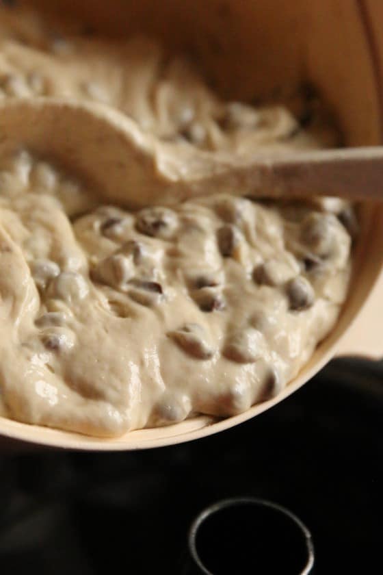 spooning banana chocolate chip batter into bundt pan