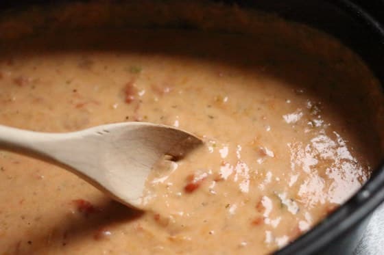 stirring warm cheese dip in roasting pan