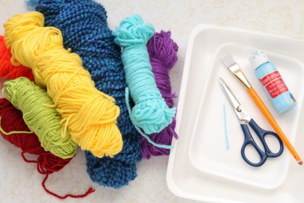 yarn, scissors, plastic sewing needle, styrofoam produce trays