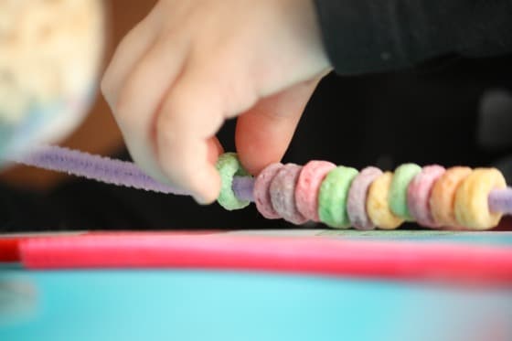 threading fruit loops onto pipe cleaners for the birds