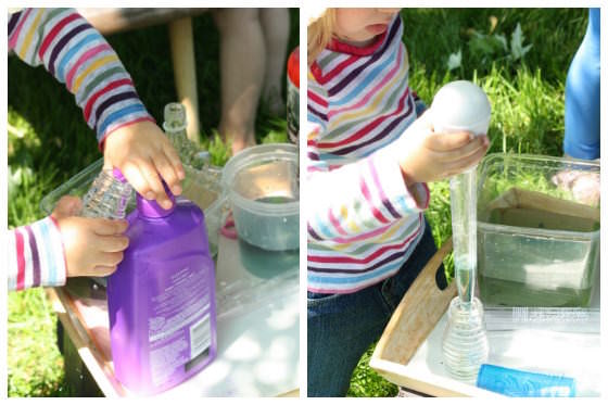 toddler adding soap and coloured water to glass bottles