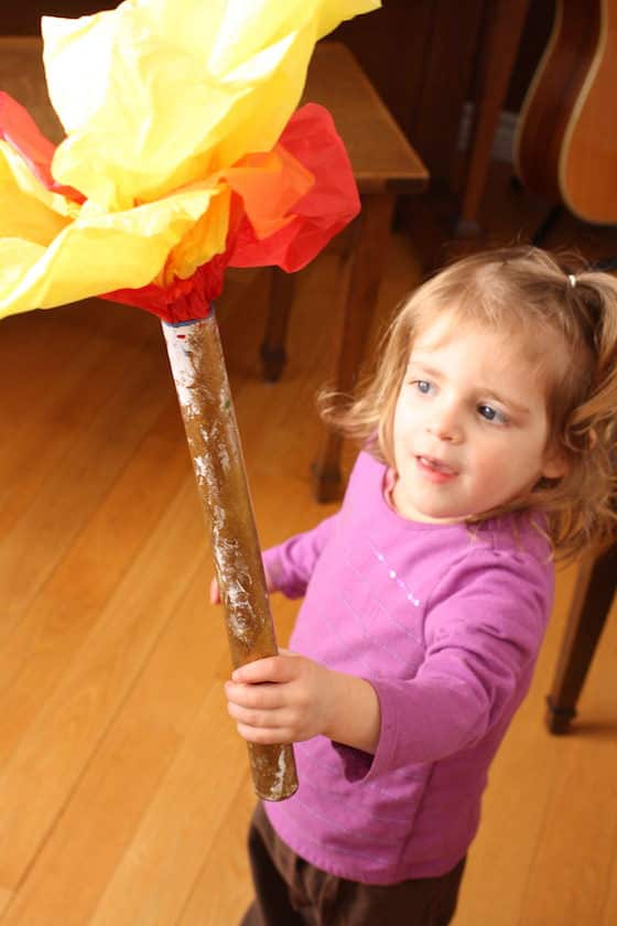 toddler holding Olympic torch made with cardboard roll and tissue paper