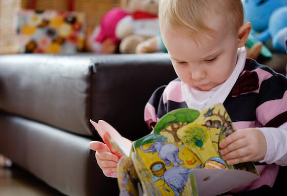 toddler looking at book from home library
