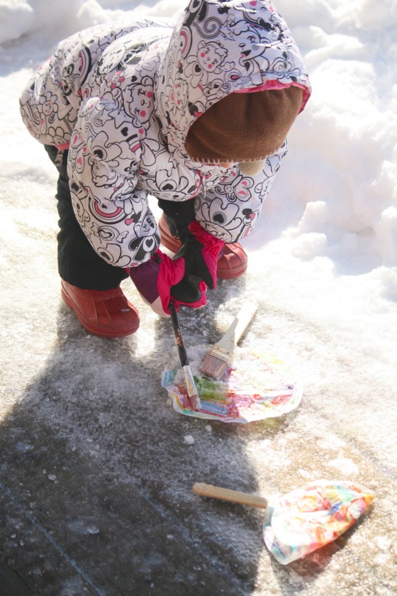 toddler painting coffee filters with snow