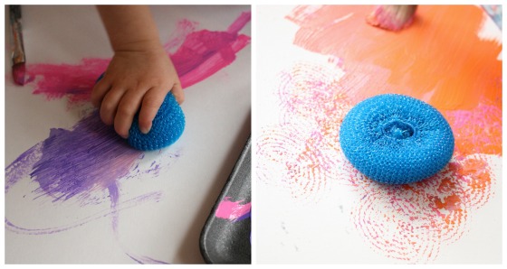 toddler painting with a dish scrubbie