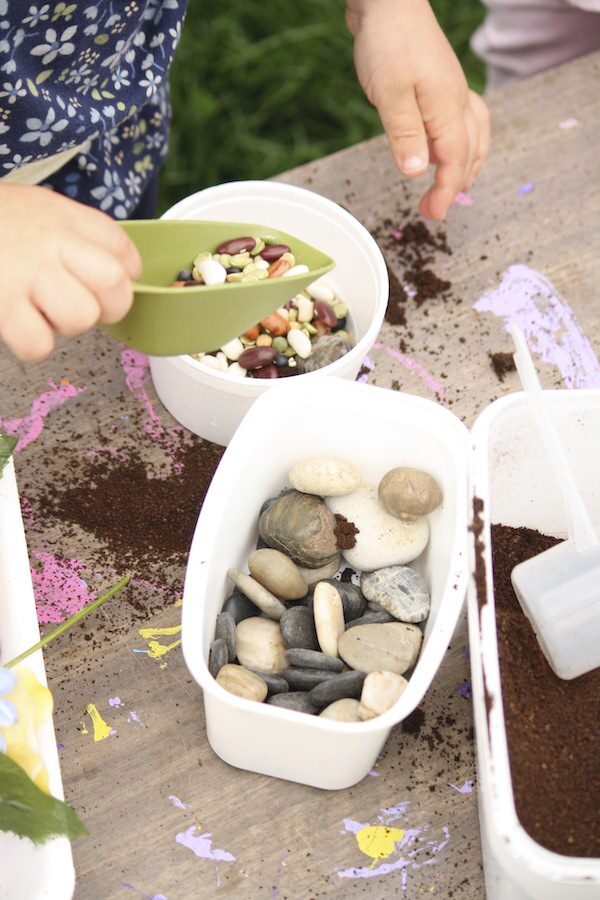 preschooler scooping dried lentils into pretend flower vase