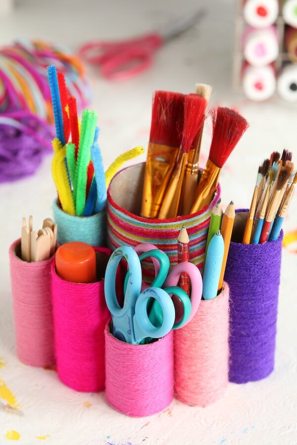 toilet roll desk organizer holding pens, pencils, scissors, paintbrushes, craft sticks and pipe cleaners