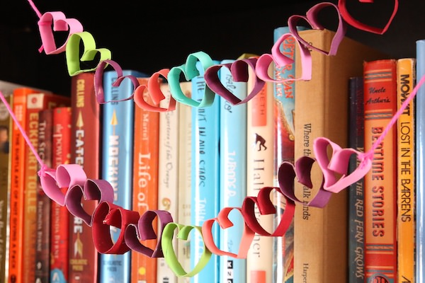 colourful tp roll heart garland strung across shelf of books