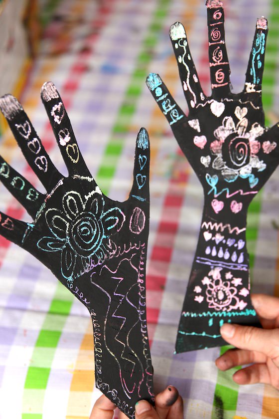 two kids' hands decorated with henna scratch art