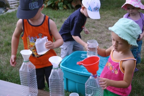 preschoolers filling plastic juice jugs with water