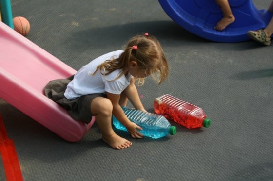 4 year old girl on slide with blue and red bottle babies