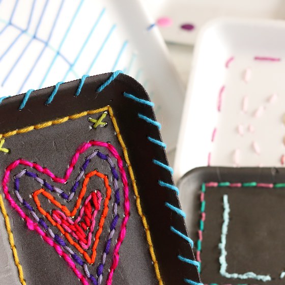 several kids sewing projects with styrofoam trays and yarn