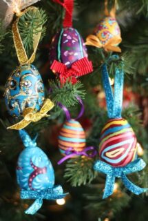 6 ornately painted plastic Easter Eggs hanging on Christmas Tree